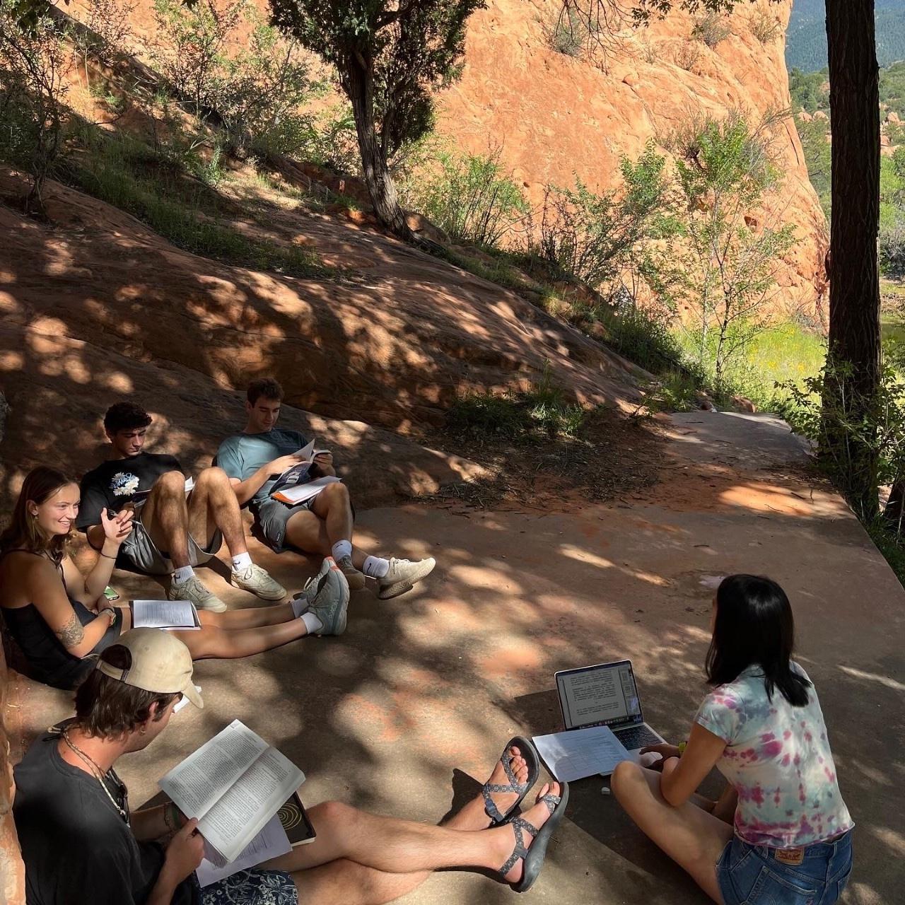 students with their laptops and book discussing their readings in the shade in Red Rocks Open Space